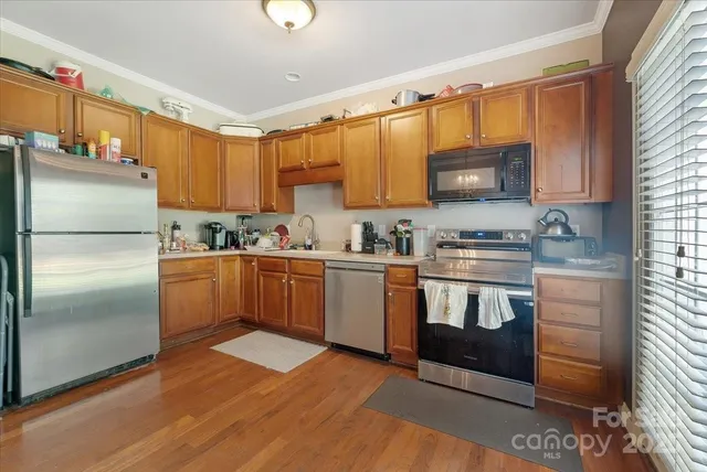 a kitchen with granite countertop a refrigerator stove top oven a sink and dishwasher