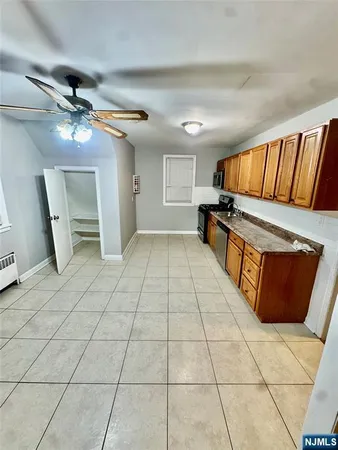 a view of an empty room with wooden floor and a ceiling fan