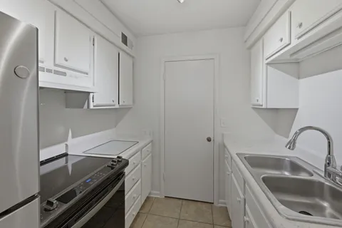 a kitchen with white cabinets sink and stove