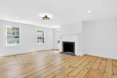 a view of empty room with wooden floor and fireplace