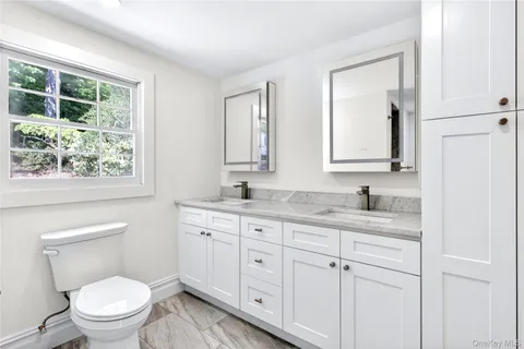 a bathroom with a granite countertop toilet a sink and mirror