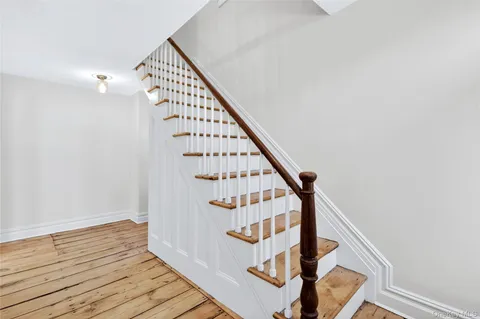 a view of staircase with wooden floor and white walls