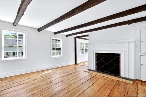 a view of an empty room with wooden floor fireplace and a window