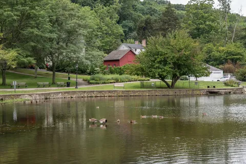 a lake view with a fountain and a lot of flower plants