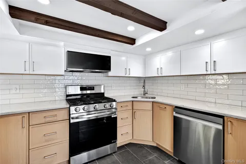 a kitchen with granite countertop a sink dishwasher stove and oven with cabinets