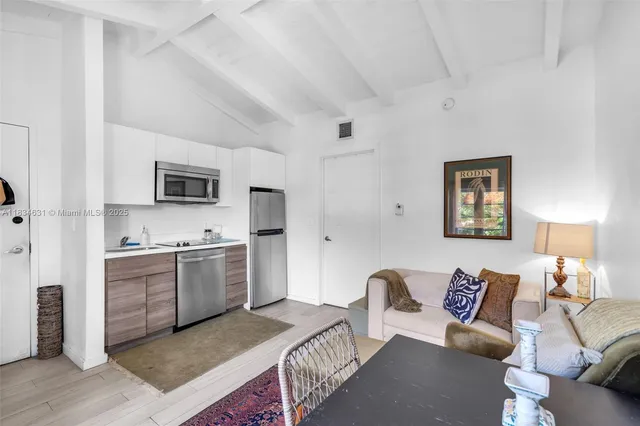 a kitchen with stainless steel appliances granite countertop a stove top oven a sink a dining table and chairs with wooden floor