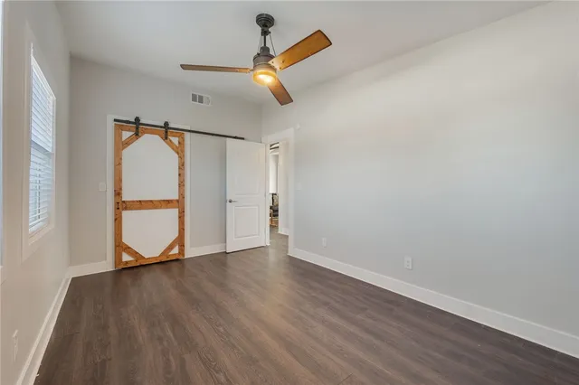 an empty room with wooden floor and a ceiling fan