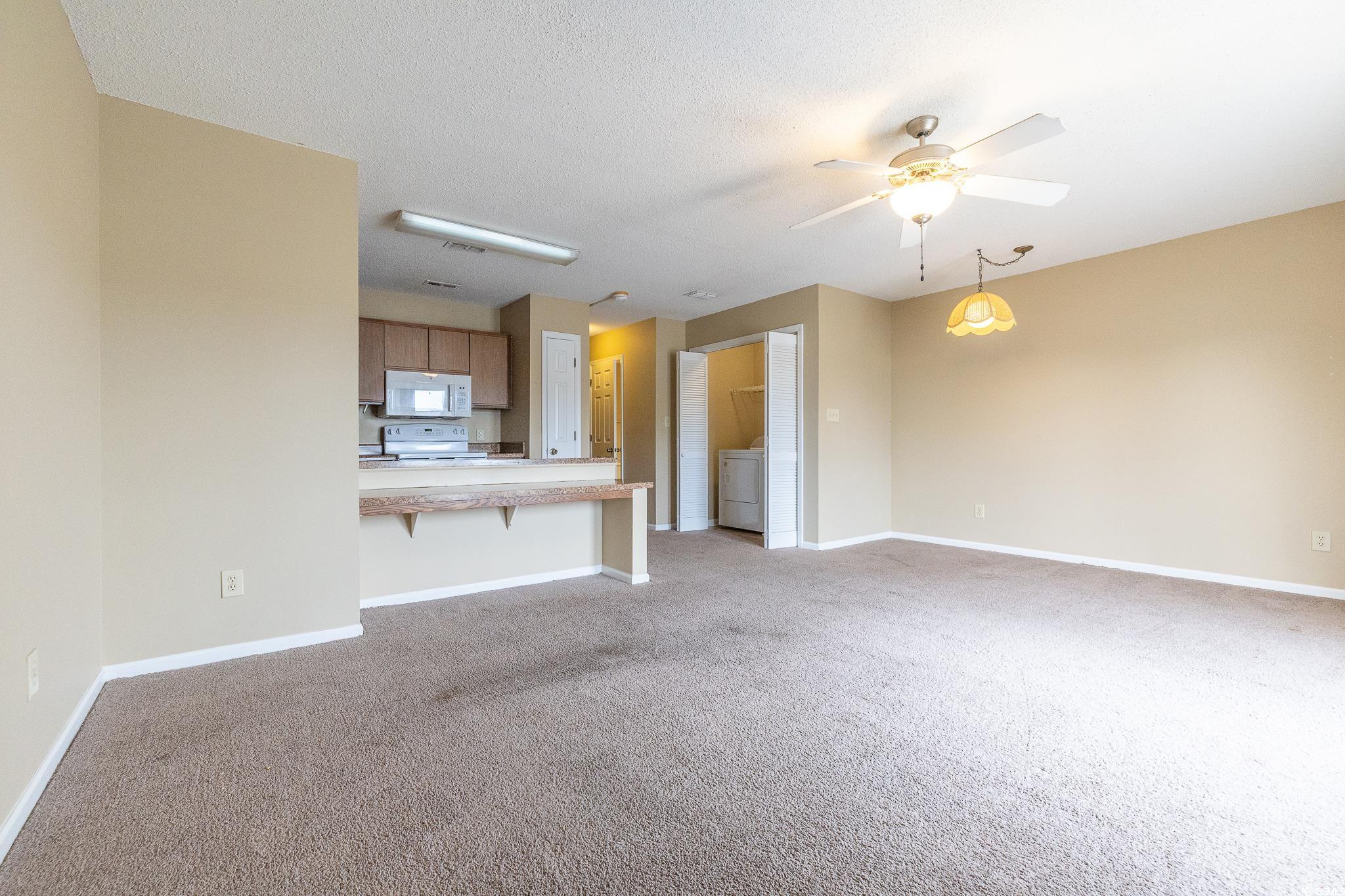 209 Double Eagle Drive, Unit F2 Surfside Beach, SC 29575 - Photo 11 of 17 Unfurnished living room with light carpet, ceiling fan, a textured ceiling, and washer / clothes dryer