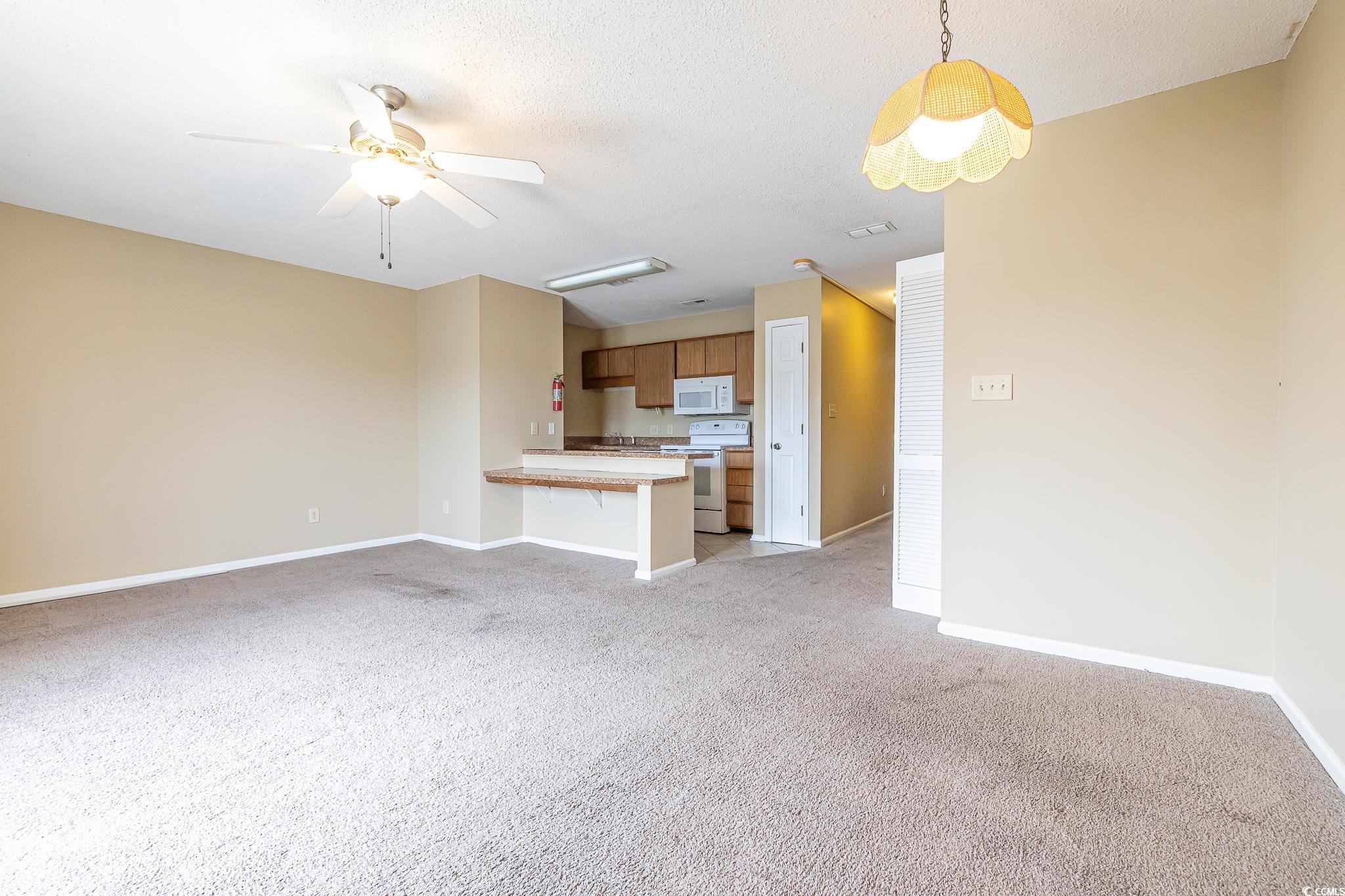 209 Double Eagle Drive, Unit F2 Surfside Beach, SC 29575 - Photo 12 of 17 Unfurnished living room featuring light carpet, ceiling fan, and a textured ceiling