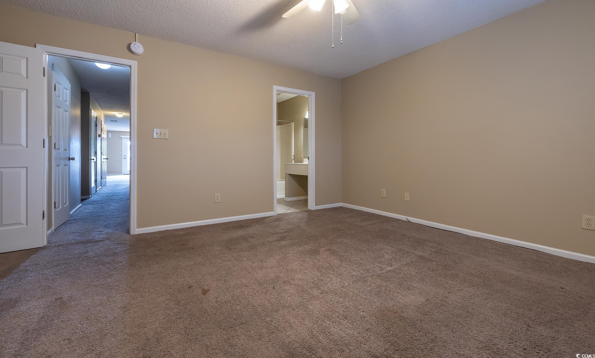 209 Double Eagle Drive, Unit F2 Surfside Beach, SC 29575 - Photo 2 of 17 Unfurnished bedroom featuring carpet flooring, a textured ceiling, ensuite bath, and a ceiling fan