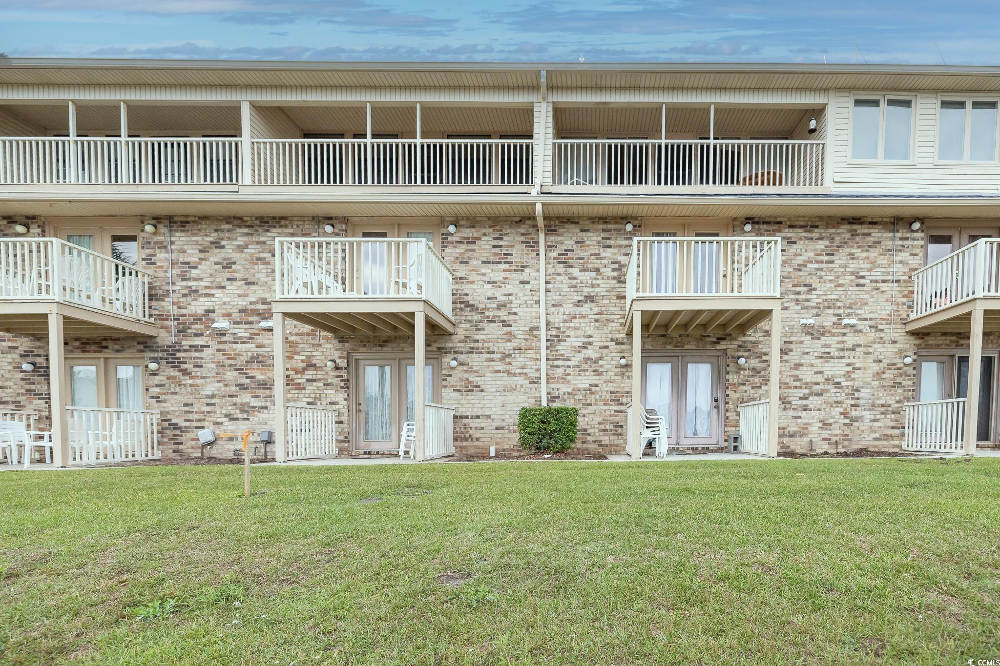 209 Double Eagle Drive, Unit F2 Surfside Beach, SC 29575 - Photo 5 of 17 Rear view of property with a balcony, a lawn, and brick siding