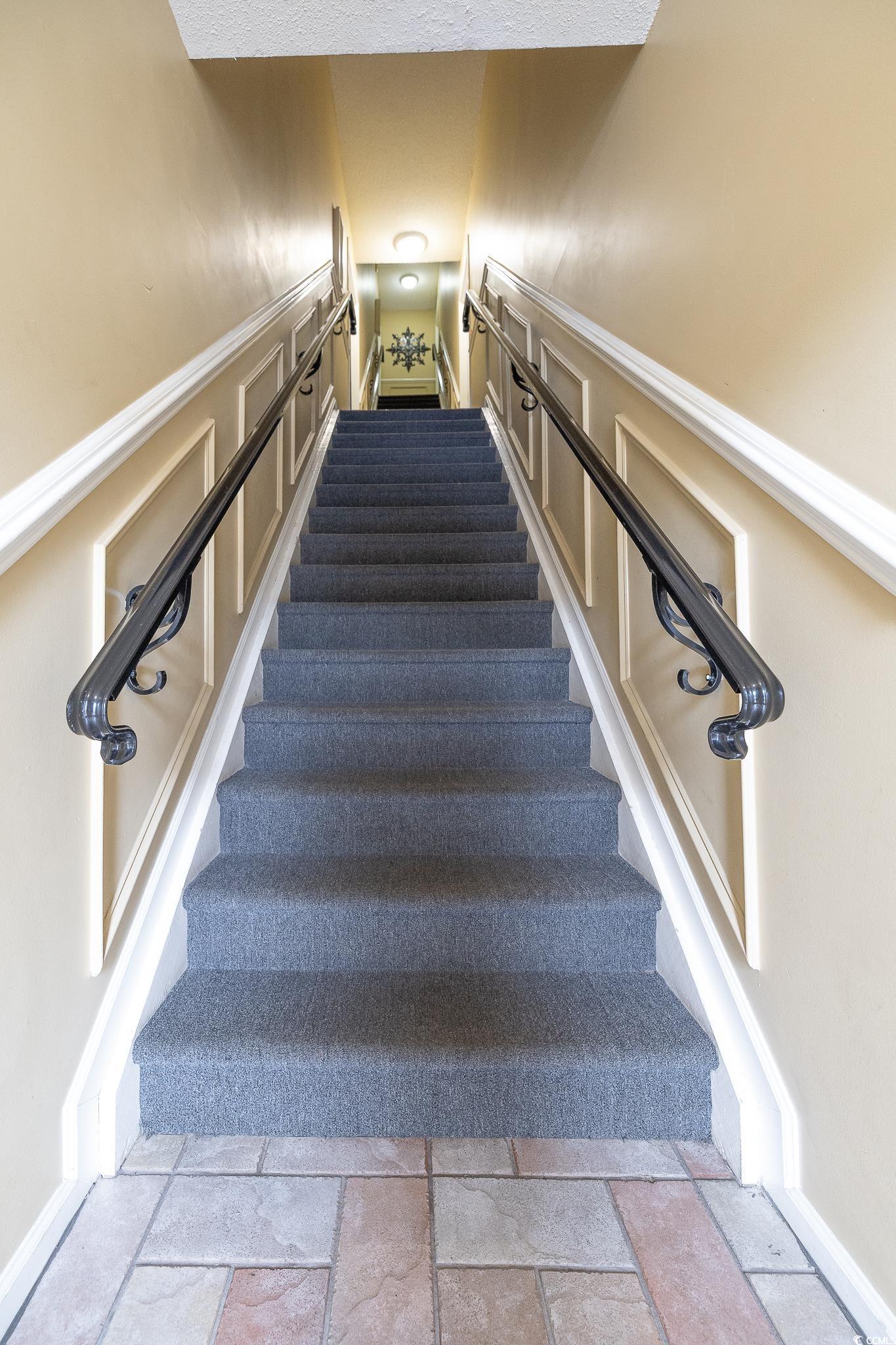 209 Double Eagle Drive, Unit F2 Surfside Beach, SC 29575 - Photo 7 of 17 Stairs featuring a decorative wall and stone tile floors