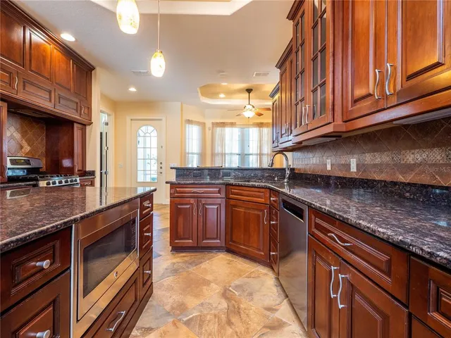 a kitchen with stainless steel appliances granite countertop a stove a sink and a microwave