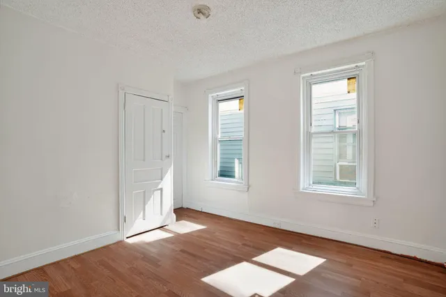 an empty room with wooden floor and windows