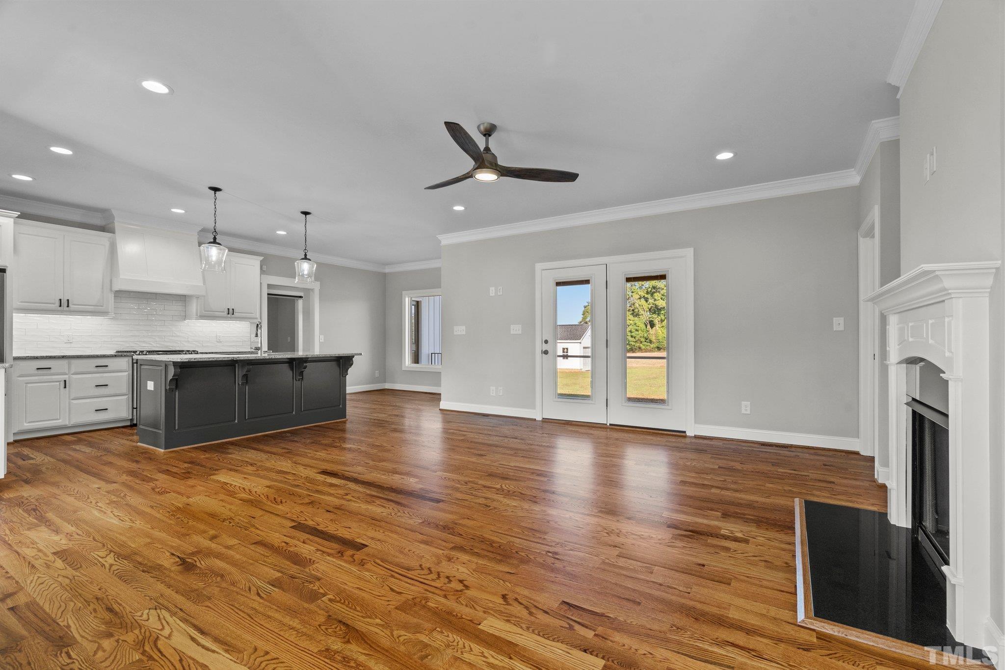 5901 Harvest Rdg Road Battleboro, NC 27809 - Photo 14 of 33 an empty room with wooden floor a kitchen view and a fireplace