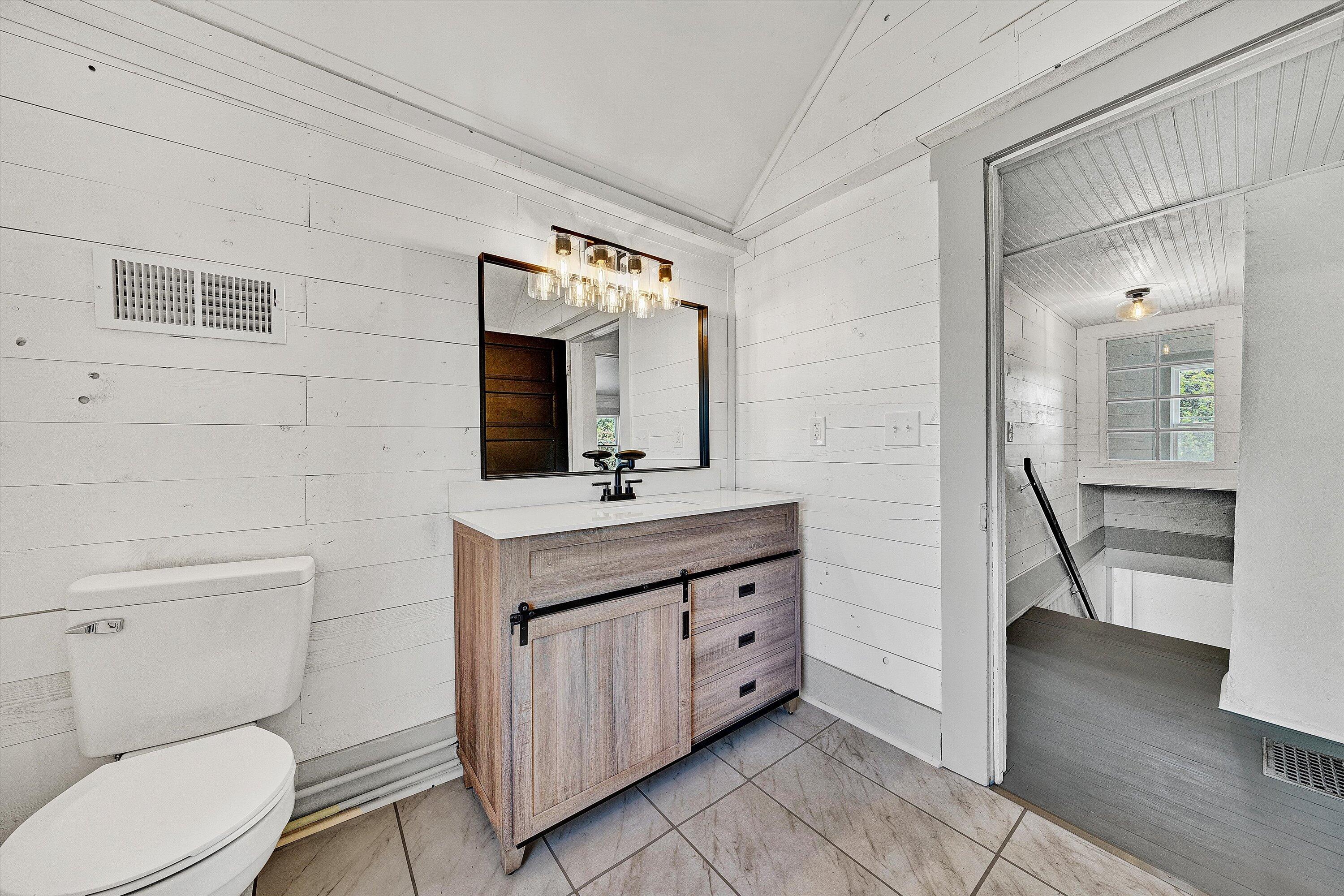 402 7th Street Salem, VA 24153 - Photo 24 of 32 a bathroom with a toilet a sink a mirror and a wooden floor
