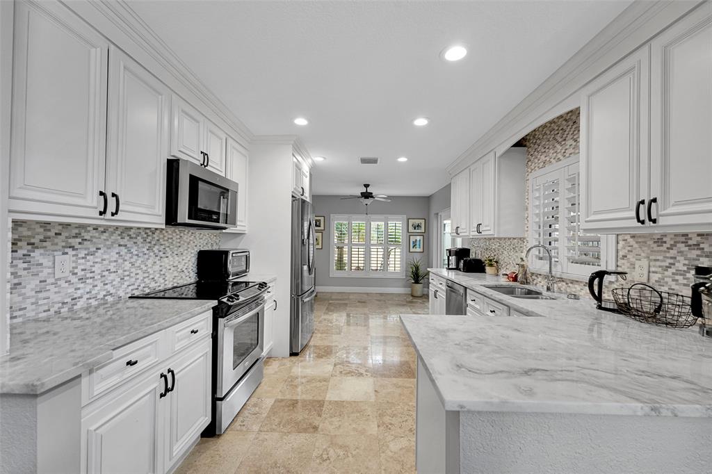 3588 Sahara Springs Boulevard Pompano Beach, FL 33069 - Photo 11 of 41 a kitchen with stainless steel appliances granite countertop a sink stove and cabinets