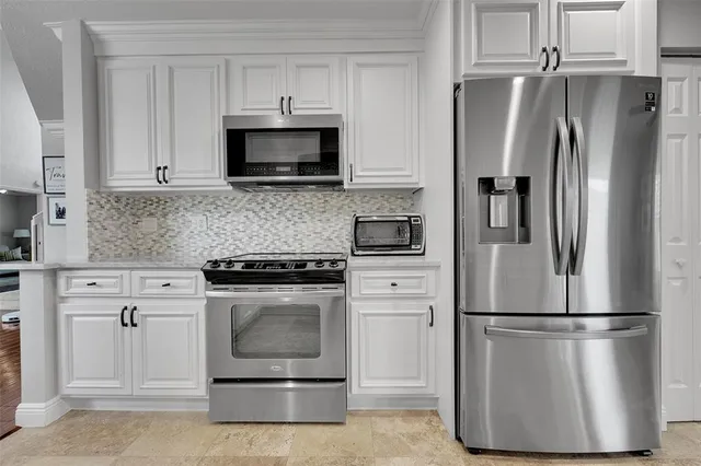 a kitchen with stainless steel appliances granite countertop white cabinets sink and window
