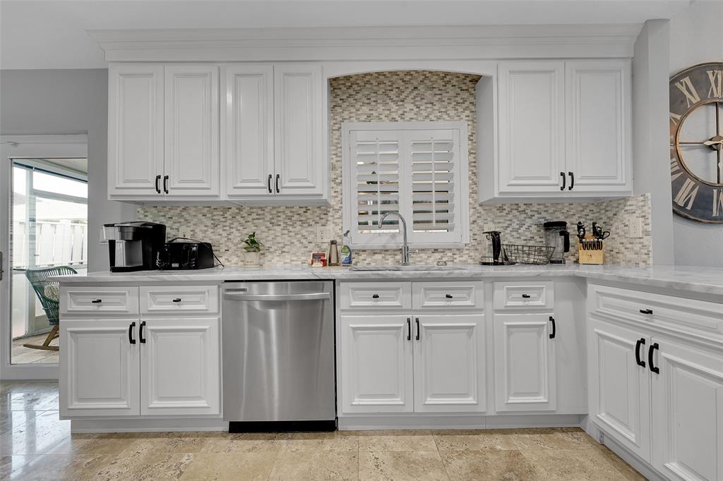 3588 Sahara Springs Boulevard Pompano Beach, FL 33069 - Photo 13 of 41 a kitchen with stainless steel appliances granite countertop white cabinets sink and window