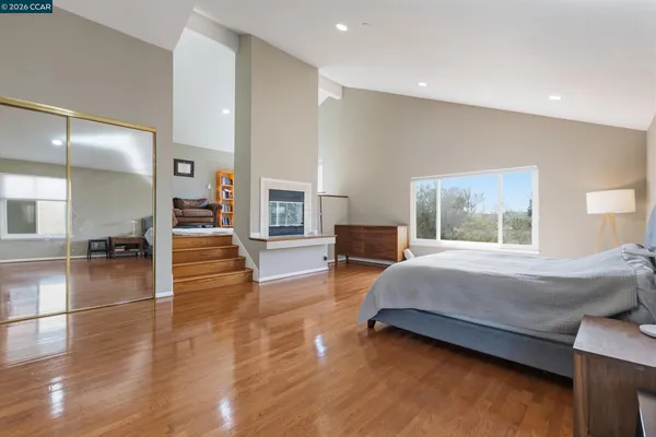 a spacious bedroom with a bed and wooden floor