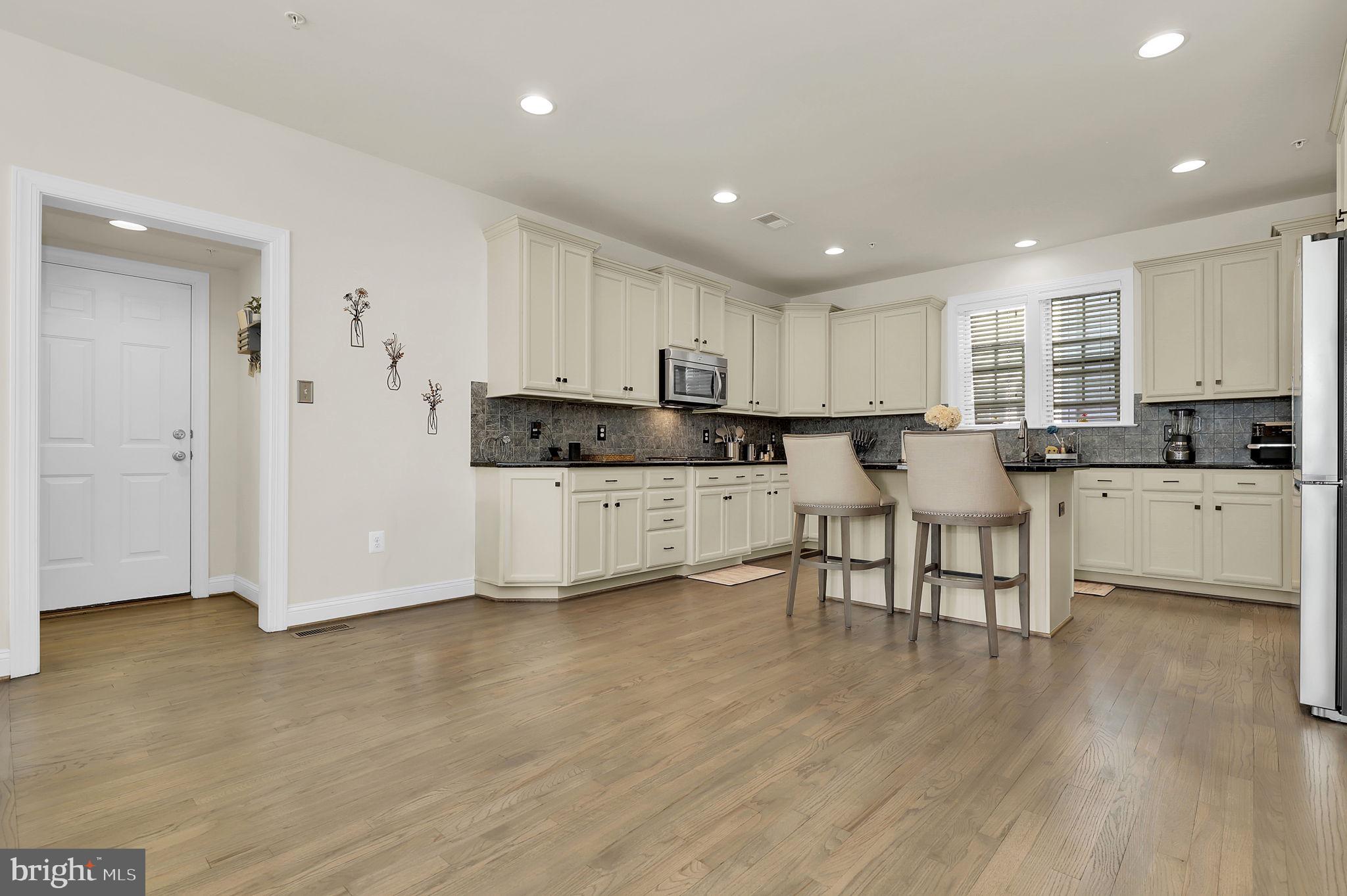 1305 Moore Spring Court Brunswick, MD 21716 - Photo 11 of 64 a kitchen with stainless steel appliances kitchen island granite countertop a stove a sink a refrigerator and white cabinets with wooden floor