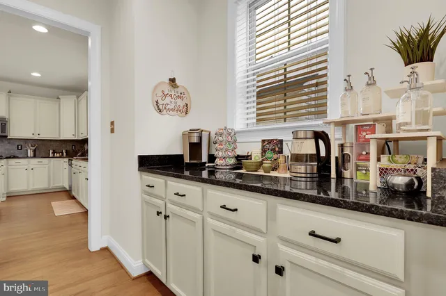 a kitchen with granite countertop a sink and white cabinets