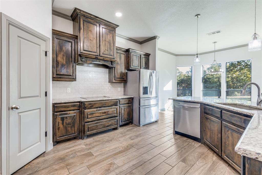 1029 Sunflower Paradise, TX 76073 - Photo 11 of 38 a kitchen with stainless steel appliances granite countertop a refrigerator a stove and a sink with wooden floor