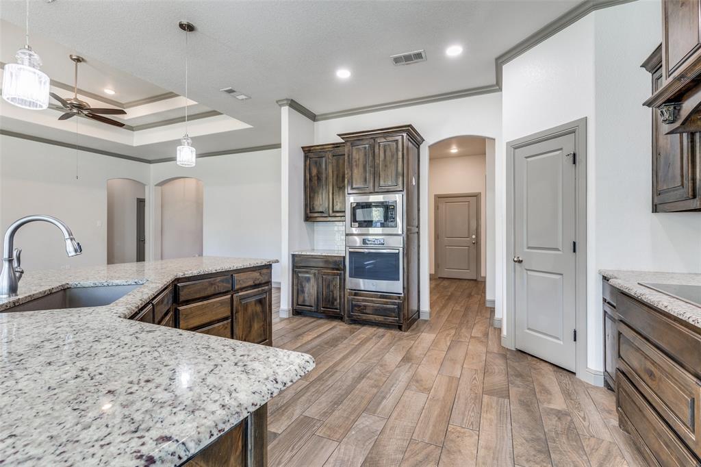 1029 Sunflower Paradise, TX 76073 - Photo 12 of 38 a kitchen with stainless steel appliances granite countertop a refrigerator a stove and a sink with wooden floor