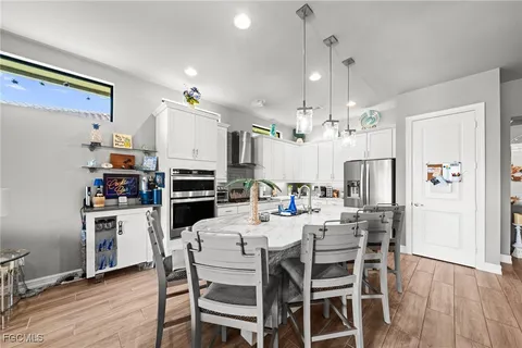 a kitchen with stainless steel appliances kitchen island granite countertop a refrigerator a stove top oven a sink dishwasher and a dining table with wooden floor
