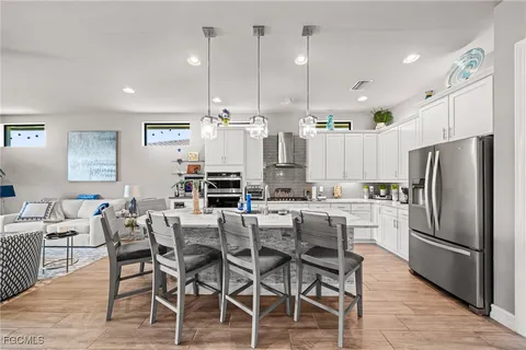 a kitchen with stainless steel appliances kitchen island granite countertop a dining table chairs refrigerator and sink