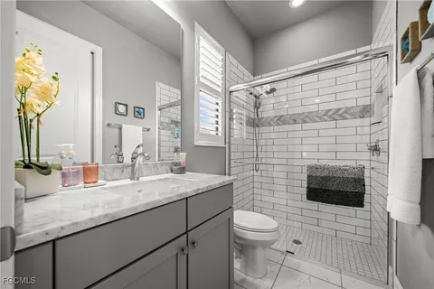 a bathroom with a granite countertop sink a toilet and a mirror