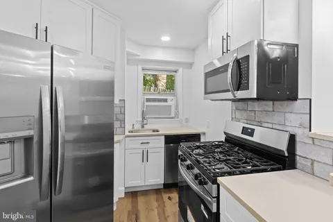 a kitchen with stainless steel appliances granite countertop a refrigerator a sink a stove with wooden cabinets