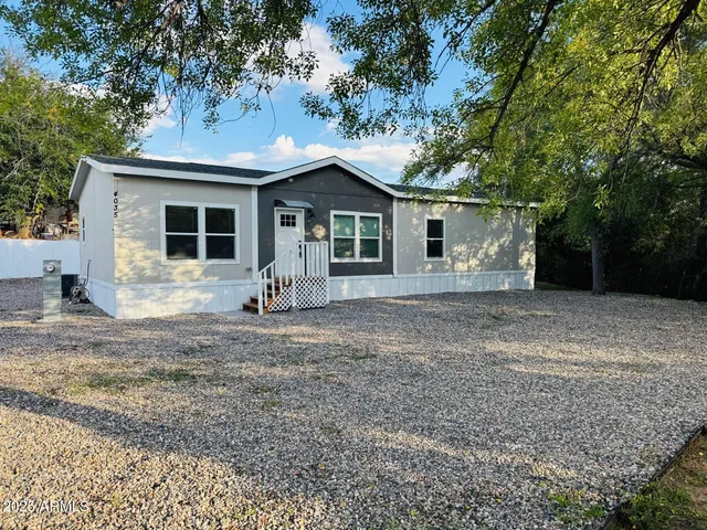 a front view of house with yard and trees in the background