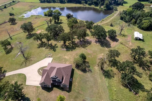 an aerial view of a house with a yard and lake view