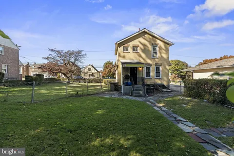 a view of a white house next to a yard with big trees