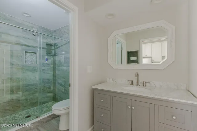 a bathroom with a shower sink vanity mirror and toilet