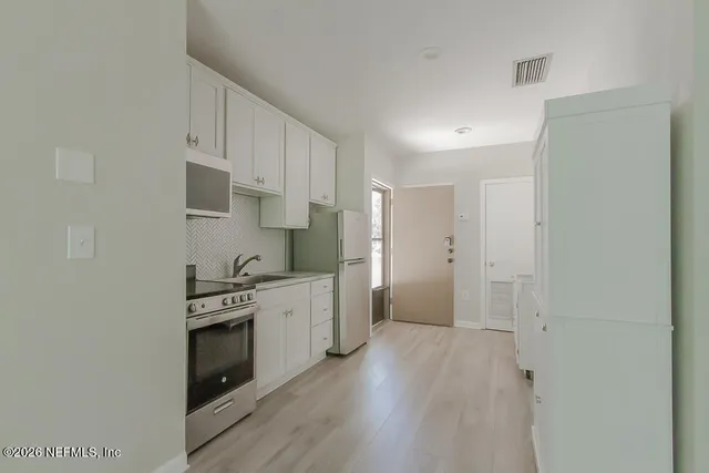 a kitchen with stainless steel appliances white cabinets and wooden floor