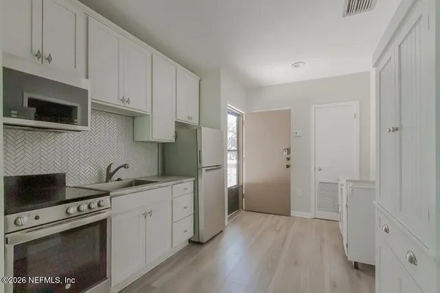 a kitchen with stainless steel appliances white cabinets and a stove top oven