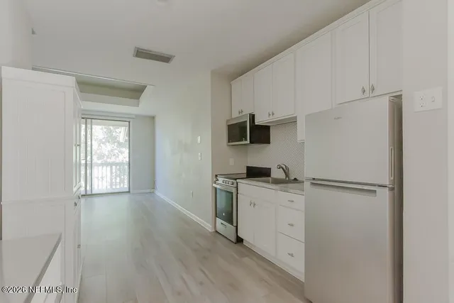 a kitchen with a refrigerator a stove top oven and cabinets