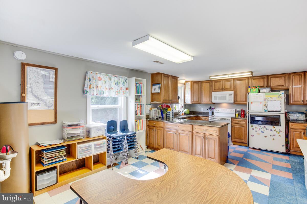 4425 Solomons Island Road Huntingtown, MD 20639 - Photo 5 of 65 a large kitchen with stainless steel appliances granite countertop a stove a sink dishwasher a dining table and chairs with wooden floor
