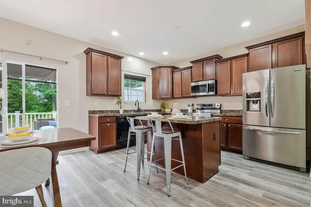 a kitchen with granite countertop stainless steel appliances white cabinets sink and a granite counter top