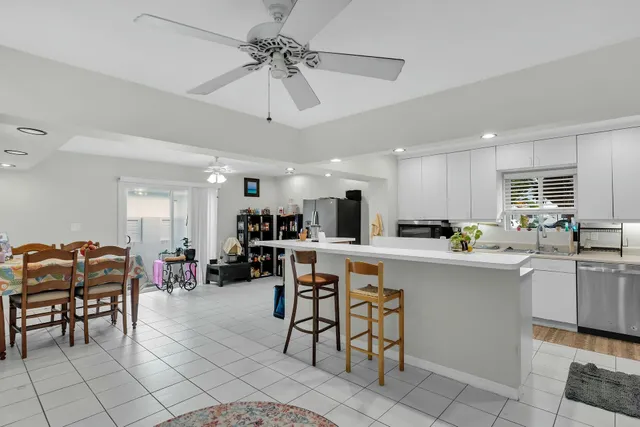 a kitchen with stainless steel appliances a table chairs refrigerator and cabinets