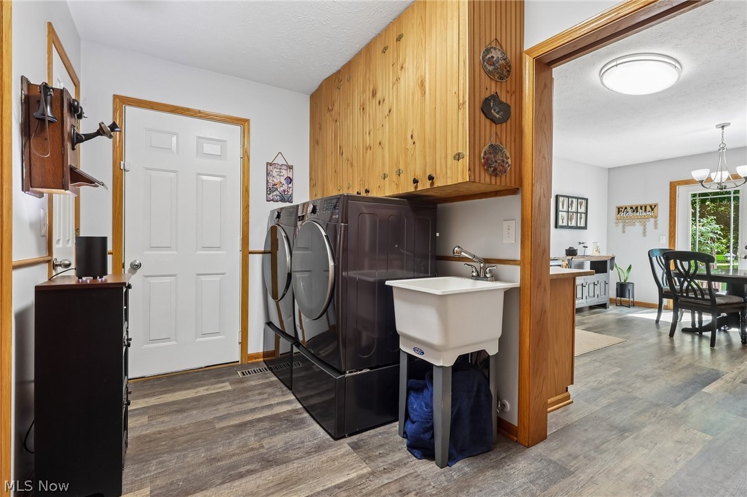 3213 Bates Road Madison, OH 44057 - Photo 29 of 45 Dedicated laundry area featuring wood-finish flooring, light wood cabinetry, and a utility sink