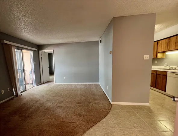 a view of an empty room and kitchen