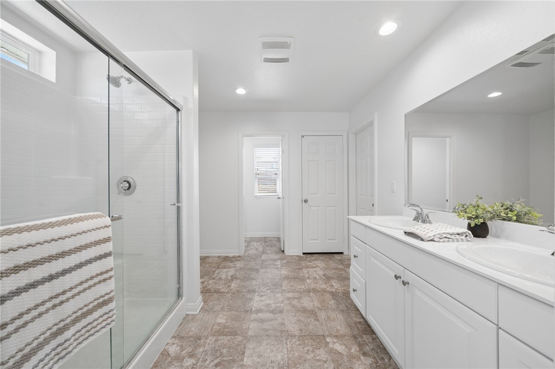 20130 Curaco Court Riverside, CA 92507 - Photo 24 of 43 Primary bathroom with dual sinks, white cabinetry, and a glass-enclosed shower.