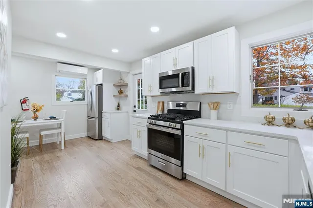 a kitchen with white cabinets stainless steel appliances and wooden floor