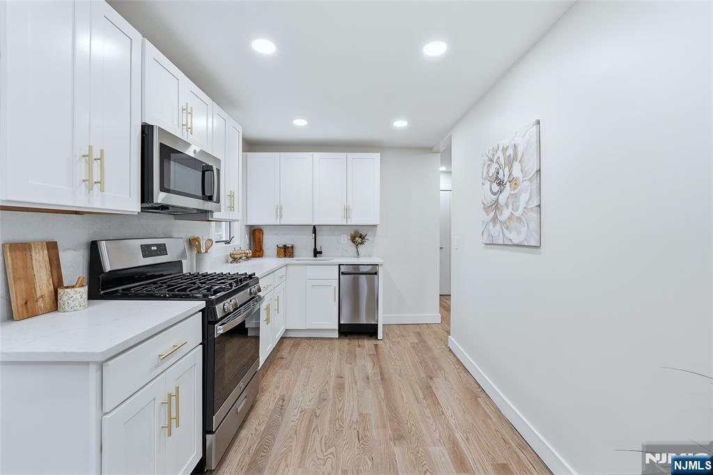 20 Dojean Court Bergenfield, NJ 07621 - Photo 9 of 30 a kitchen with granite countertop a stove top oven a sink dishwasher a refrigerator white cabinets and wooden floor