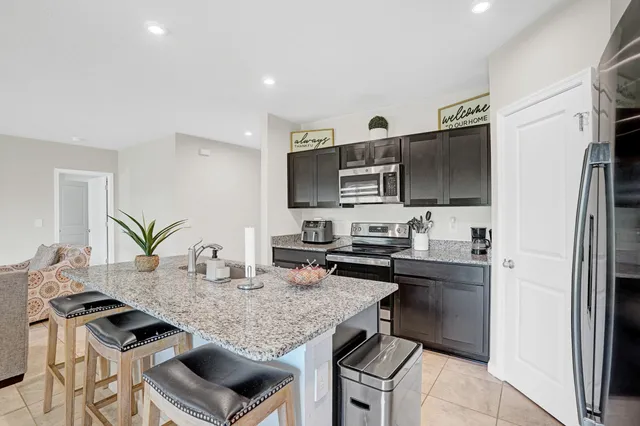a kitchen with stainless steel appliances kitchen island granite countertop a stove refrigerator and microwave
