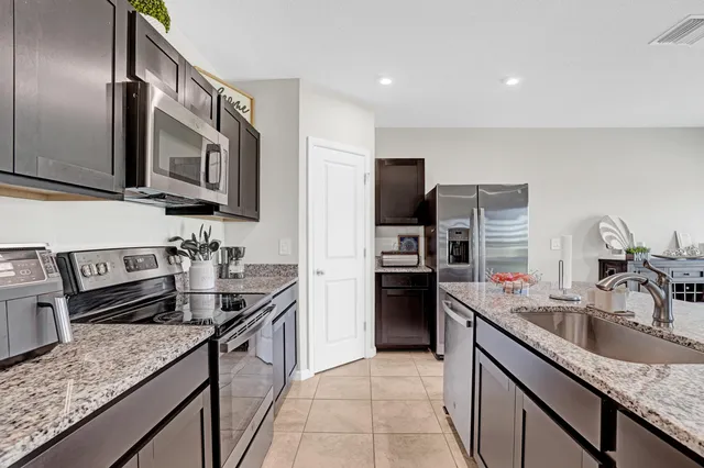a kitchen with granite countertop a sink a stove and refrigerator