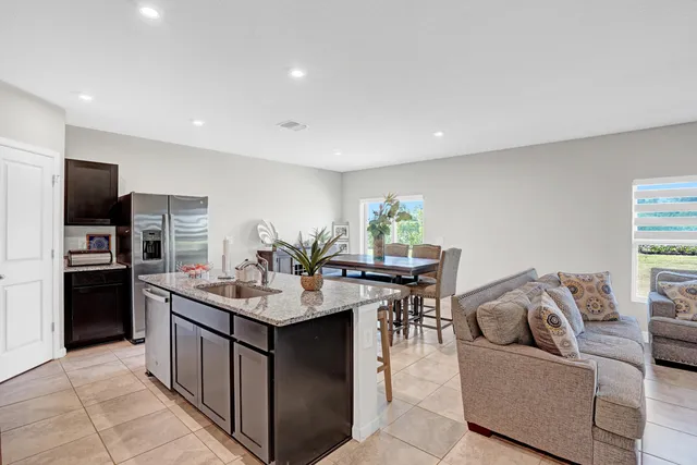 a living room with stainless steel appliances kitchen island granite countertop a sink and a refrigerator
